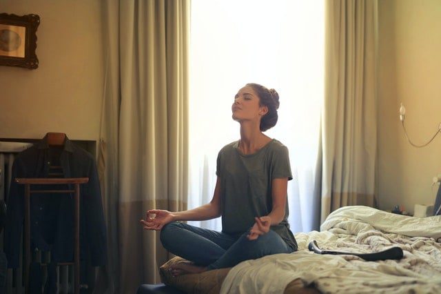 Woman meditating in her bedroom