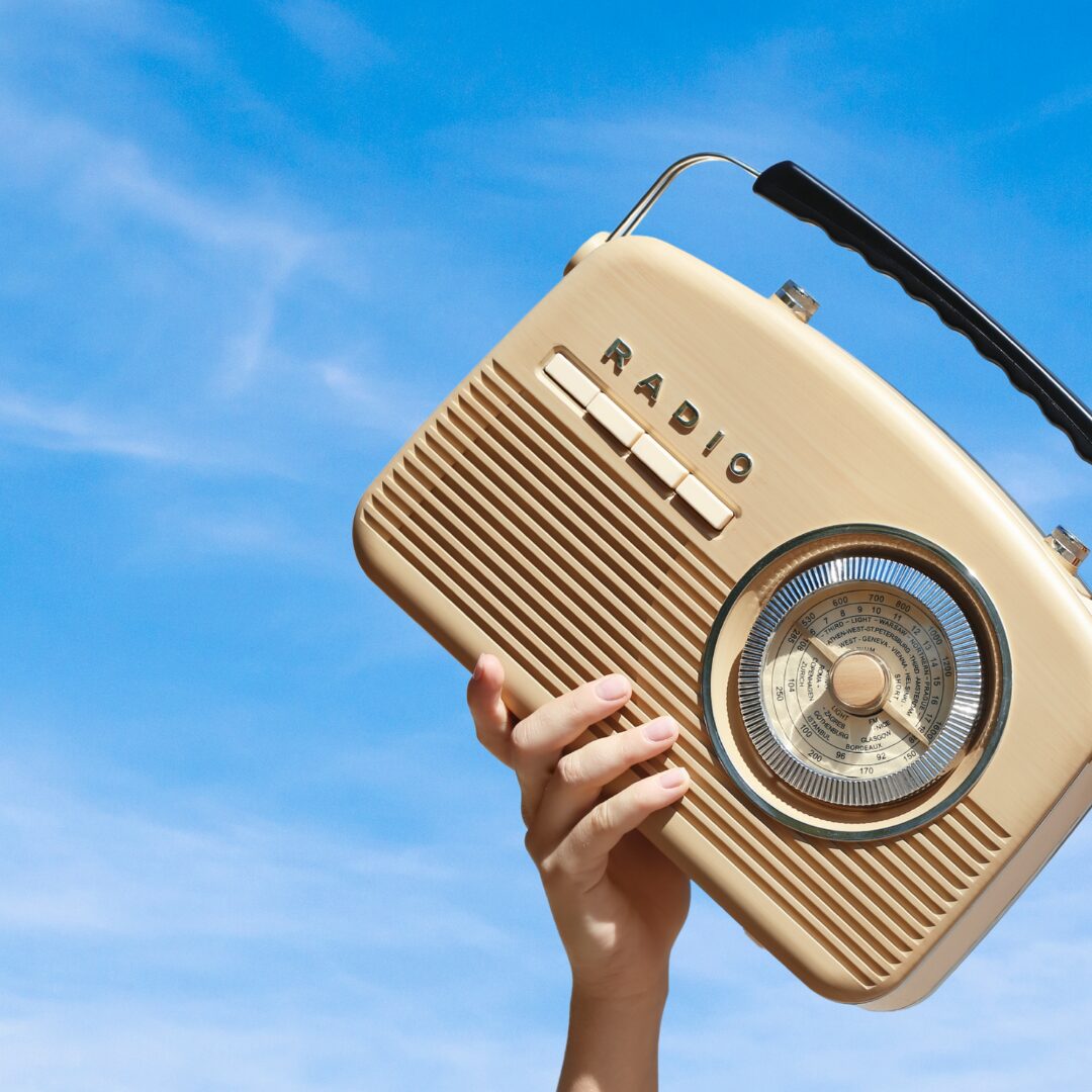 A radio being held up in front of the blue sky