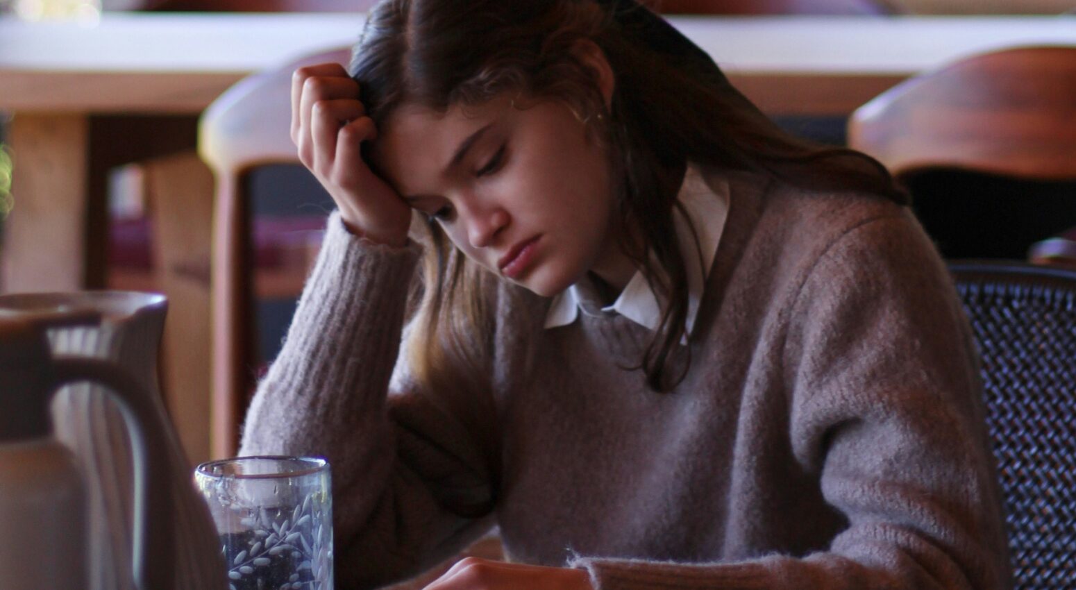 A woman in a cafe with her head in her hand looking sullen Image source: Unsplash