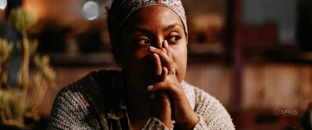 A woman with her hands held together in front of her face, looking ahead somberly
Image source: Unsplash

