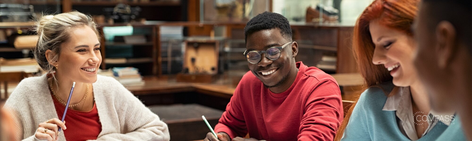 Diverse group of college students studying together in a campus library, representing connection, academic success, and improved access to mental health care for young adults.