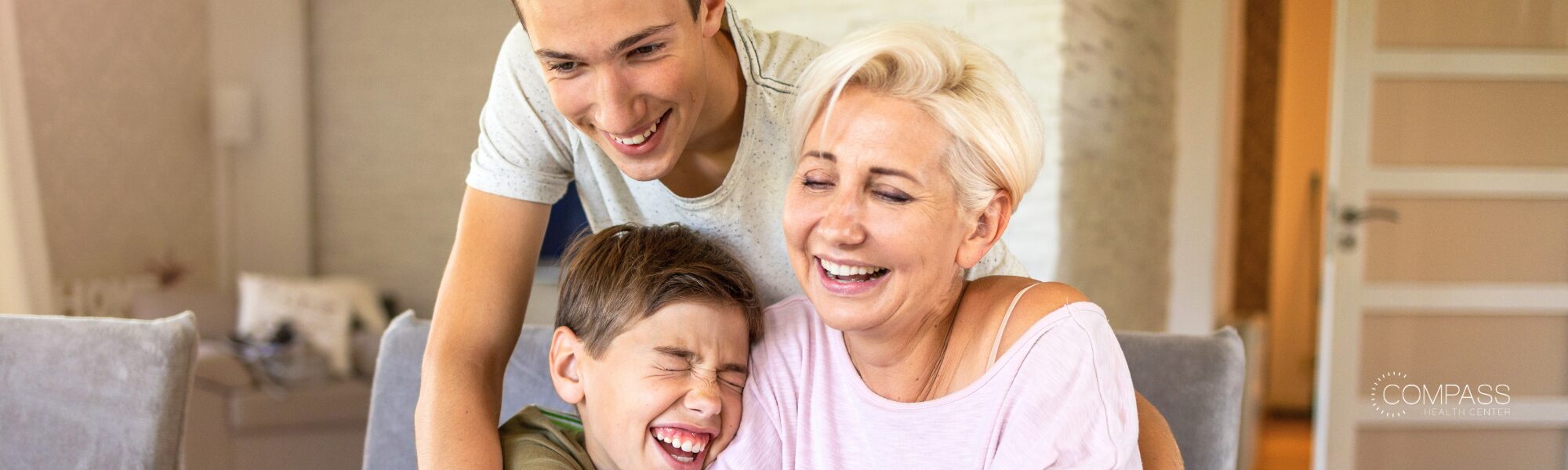 A grandmother and two children share a joyful moment together at home.