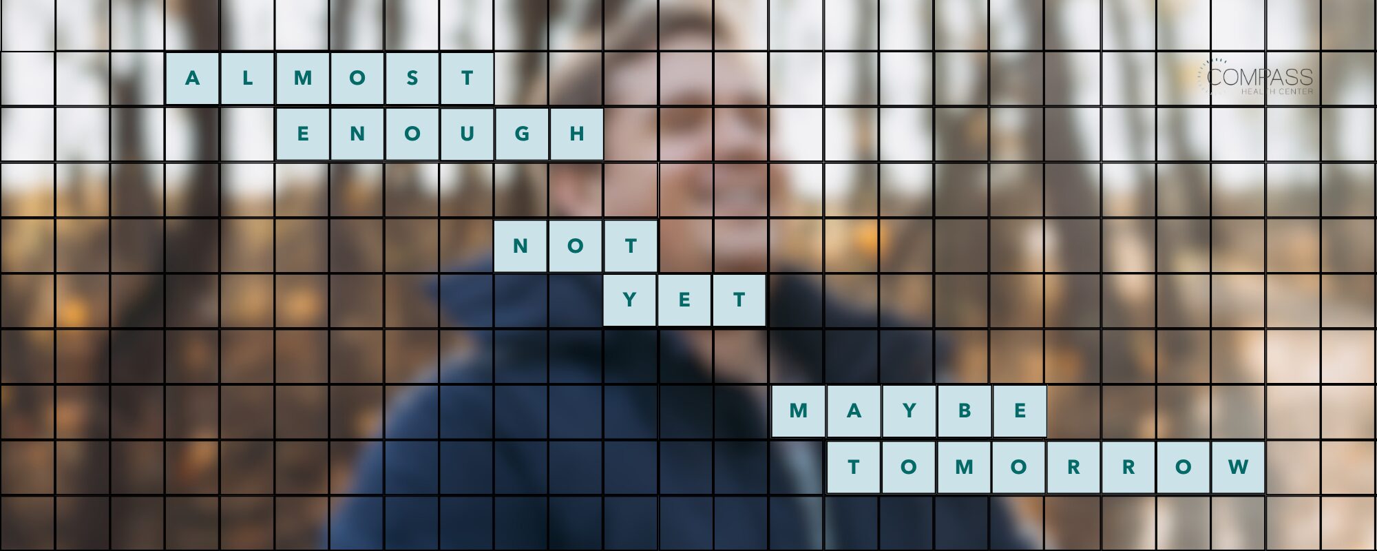 A blurred photo of a smiling person in a dark blue jacket outdoors among autumn trees, overlaid with a black grid. Light blue letter tiles in the grid spell out a crossword-style phrase: “Almost enough. Not yet. Maybe tomorrow.” The Compass Health Center logo appears in the top right corner.